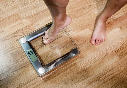 体重减少那女人在秤上称体重.照片