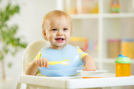 快乐的小男孩用勺子自己吃东西