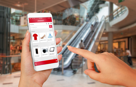 在背景中的车智能手机在线购物的女人手里.购物中心在背景中照片