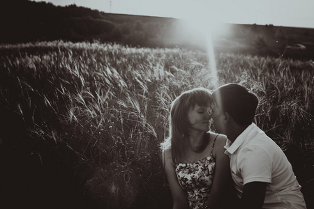 浪漫的黑白色照片夫妇站和接吻背景夏天草地日落