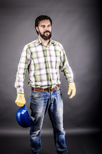 年轻的工程师，一个手里拿着他的安全帽的肖像