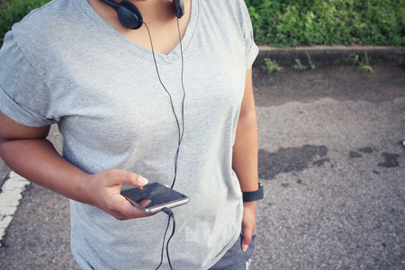 女人在耳机与智能手机上听音乐