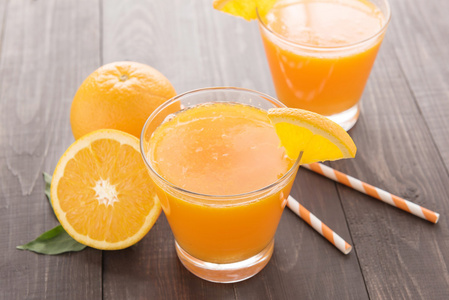 鲜橙汁和木制的桌子上的橘子