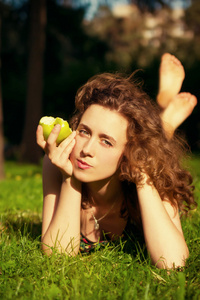 年轻漂亮的女人吃苹果在户外