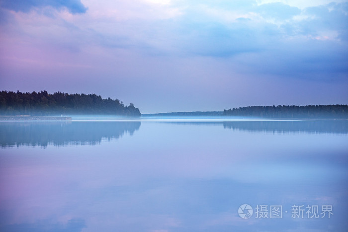 雾蒙蒙的清晨日出在平静的镜子上浮出水面的湖面