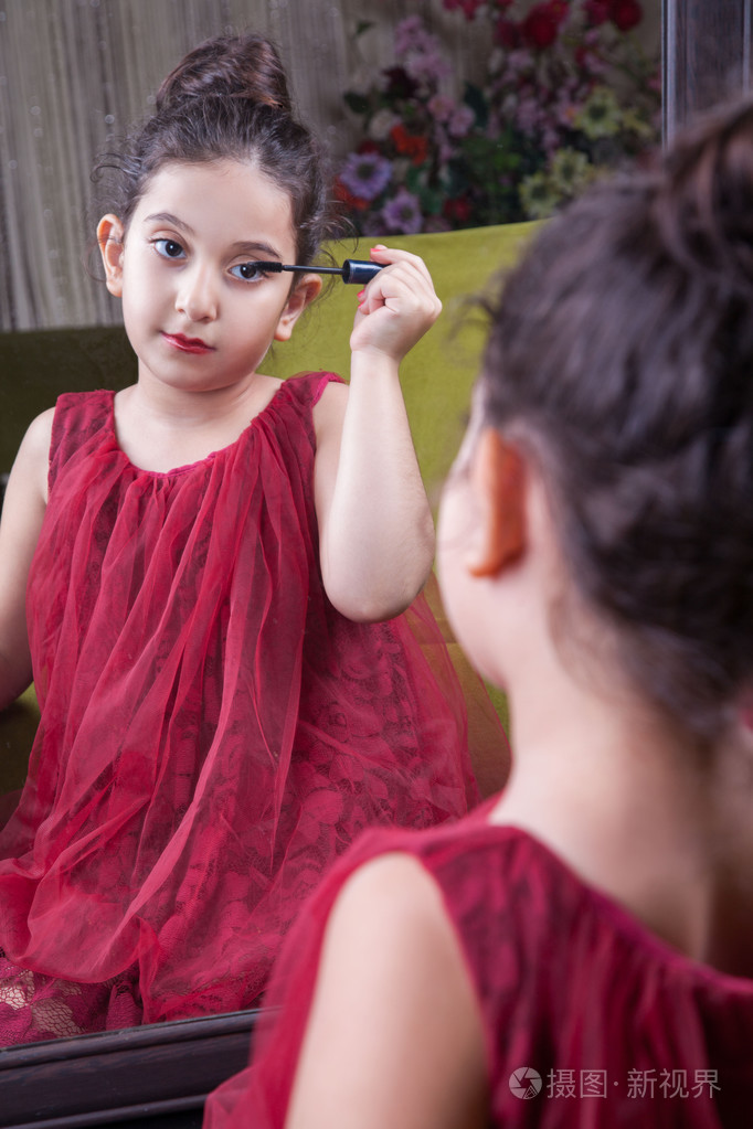 小美丽阿拉伯中东女孩漂亮的红裙子,做化妆在家仔细地在镜子的嘴唇.