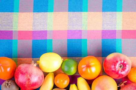 五颜六色的格子厨房毛巾上的新鲜水果。 夏天回来