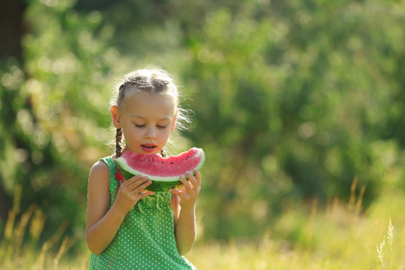 在草坪上吃西瓜的小女孩