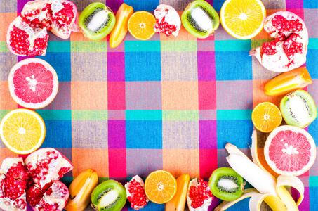 多彩花纹的厨房用毛巾擦的新鲜水果。原料和素食饮食的框架。切片橙 柿子 猕猴桃 橘 香蕉 柠檬 苹果 柚子 石榴