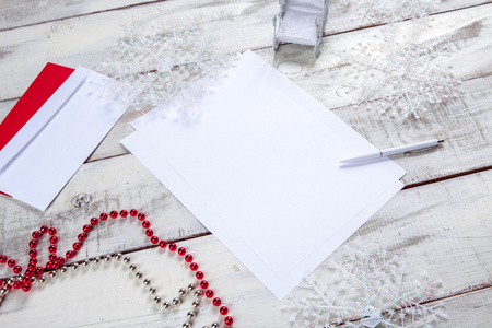木桌上的白纸上有一支钢笔和圣诞装饰品。 圣诞模型概念