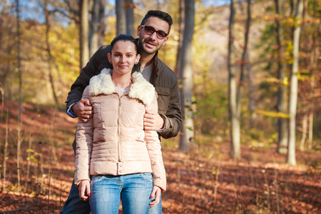 微笑在森林里的年轻夫妇在秋天