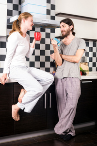 快乐微笑白种人对年轻情侣在厨房喝着早晨咖啡，互相交谈