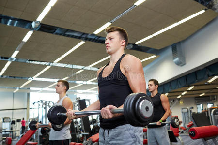 一群男子在健身房用杠铃伸展肌肉