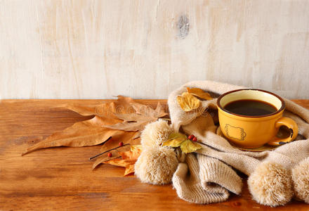 一杯秋叶黑咖啡的俯视图，木质背景上的温暖围巾。丝网图像