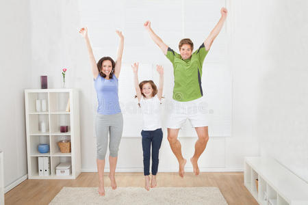 兴奋的一家人穿着运动服在家里跳跃