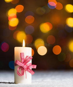 燃烧的蜡烛，在雪地里，伴随着飘散的仙女灯，背景是波基，节日的圣诞背景