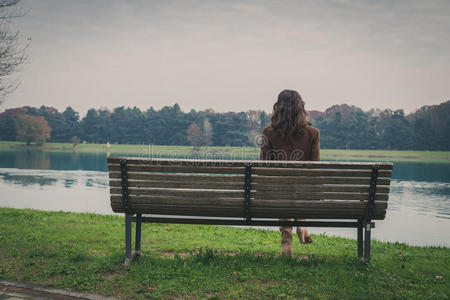 美丽的年轻女子坐在城市公园的长椅上