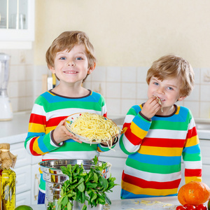 两个小家伙在国内的厨房里吃意大利面条的男孩