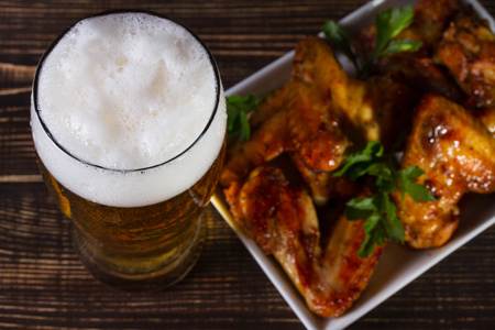 Glass 的啤酒和鸡翅膀上深色木制背景