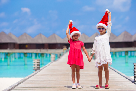 小可爱女孩红色圣诞帽，手上海滩热带度假