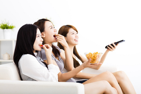 快乐的年轻女子组吃小吃，看电视