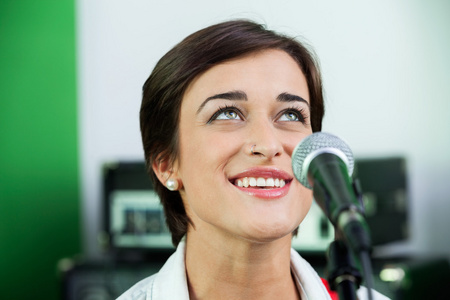 女人在录音棚看起来一边唱歌