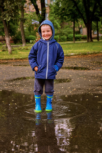 小男孩去橡胶靴在池上