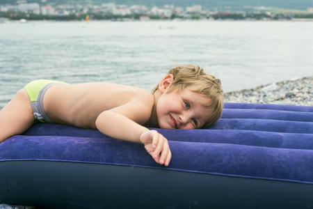 小男孩在海边的充气床垫上