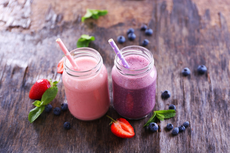 健康草莓酸奶有薄荷和周围木制背景上的浆果