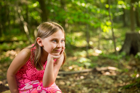 快乐的小姑娘坐在树林里看着副本空间