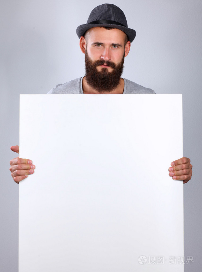 白色背景上孤立的年轻男子戴着帽子站在空白,附近的肖像