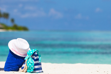 条纹袋 蓝色毛巾 太阳镜 防晒霜瓶和洁白的沙滩上穿上泳装