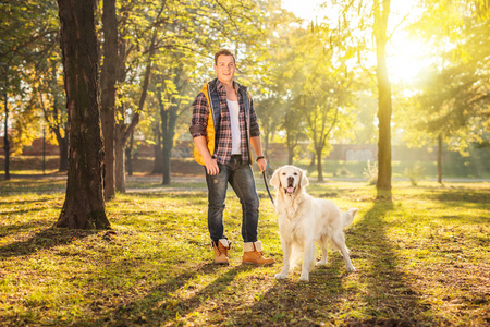 男人站在一片草地和一条狗照片