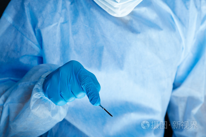 外科医生手拿手术刀,同时操作病人