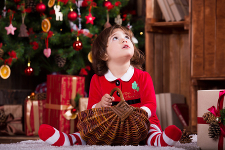 可爱的小圣诞老人女孩做梦附近圣诞树，许下一个心愿。快乐的新年气氛