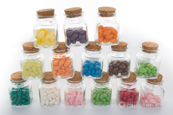 清晰的玻璃罐里的糖果和彩色糖豆从罐子里洒了