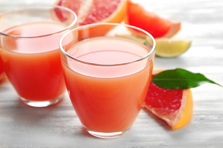 柑橘类果汁和新鲜水果轻木背景上的两杯