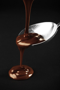 巧克力倒在黑暗的背景一把勺子