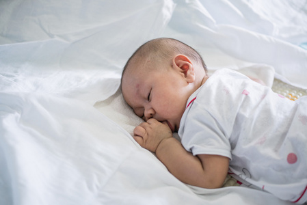 亚洲婴儿睡着白色的床单