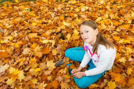 秋天的可爱的小女孩，8 岁的时候，黄色的叶子在公园玩的肖像