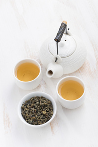 茶壶和杯绿茶在白色的木制背景