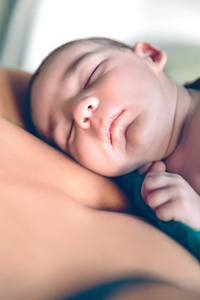刚出生的婴儿安睡在母亲胸前