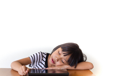 小女孩坐在木制的桌子-技术和儿童的无聊的平板电脑概念照片