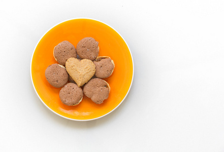 巧克力曲奇饼和奶油曲奇心在白色背景上的橙色盘形状