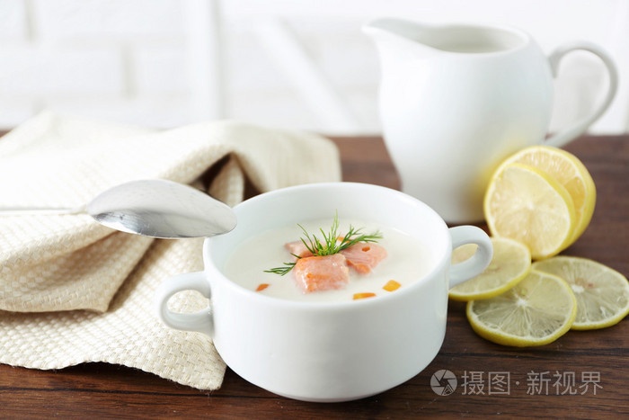 用勺子木制的桌子,片的柠檬和香料配上美味鲑鱼奶油汤