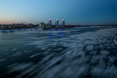 如画的城市夜景，灯光和河流，水中灯光的倒影和移动的冰在长时间的照射下拍摄