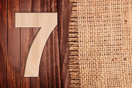 木制数字一个符号7。在木桌背景王氏麻布