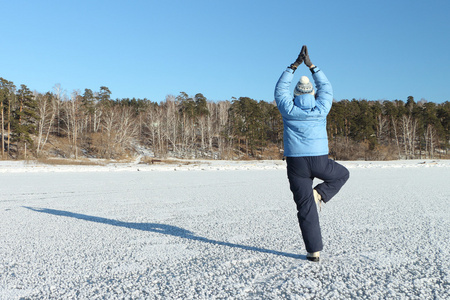 在一件蓝色的夹克上白雪覆盖的 sur 练瑜伽的女人