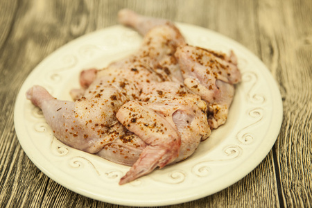 原料新鲜的鸡肉，对陶瓷板与木的背景
