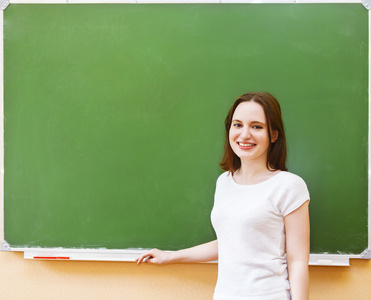 女学生站在旁边干净黑板在教室里